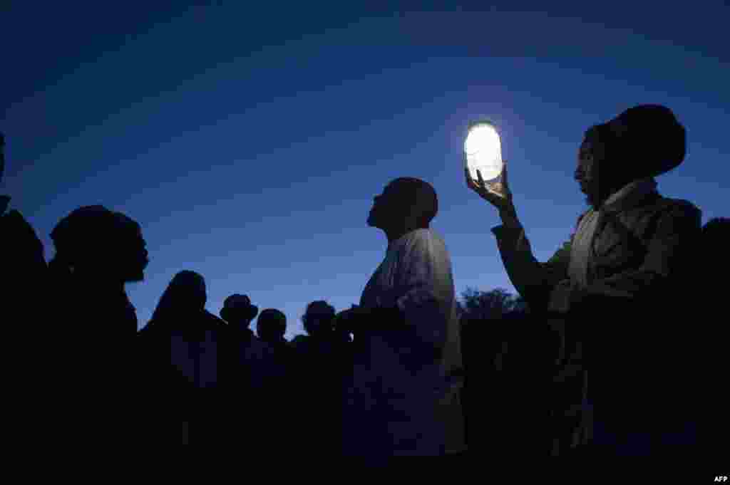 A group of activists, religious leaders and former prisoners listen to a former prisoner (C) talk about working the lime quarry during a visit to Robben Island, Dec. 14, 2013, in Cape Town, for an all night vigil to commemorate Nelson Mandela. 