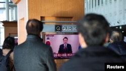 People watch a TV screen broadcasting South Korean President Yoon Suk Yeol delivering an address to the nation, at a railway station in Seoul, South Korea, Dec. 12, 2024.