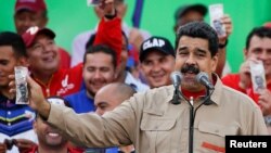 FILE - Venezuela's President Nicolas Maduro holds up a mock 100-bolivar bill depicting the president of the National Assembly Henry Ramos Allup, during a pro-government rally in Caracas, Venezuela, Dec. 17, 2016.