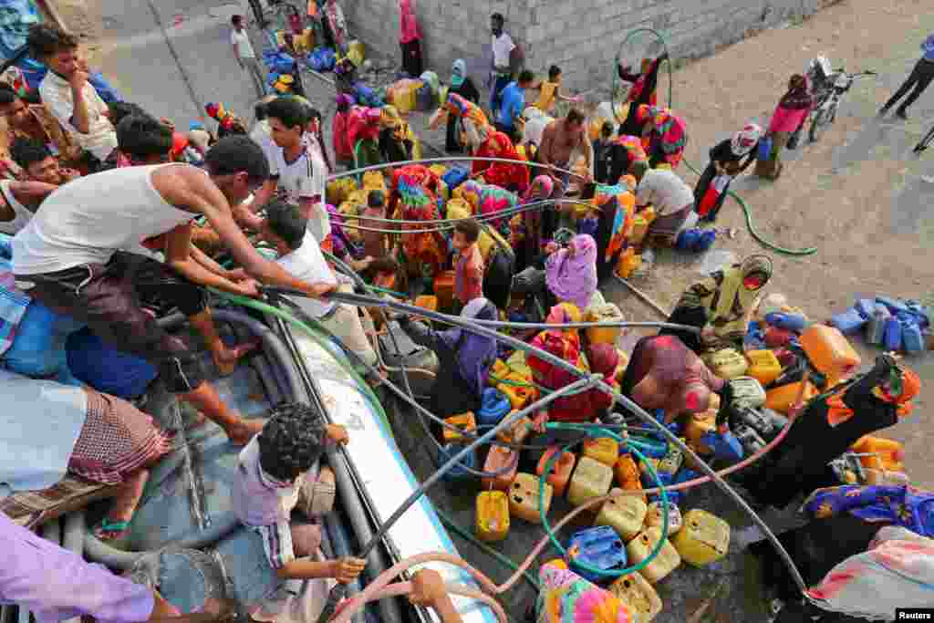 People gather around a charity tanker truck to fill up their jerrycans with drinking water in Bajil of the Red Sea province of Hodeidah, Yemen, July 29, 2017.