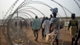 A file photo taken Jan. 19, 2016 shows displaced people walking next to a razor wire fence at the United Nations base in the capital Juba, South Sudan. 