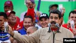 Venezuela's President Nicolas Maduro holds up a mock 100-bolivar bill depicting the president of the National Assembly Henry Ramos Allup, during a pro-government rally in Caracas, Venezuela, Dec. 17, 2016.