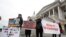 Protesters hold signs and sing outside the U.S. Capitol, Jan 31, 2020, in Washington, as Senators continue the impeachment trial for President Donald Trump.
