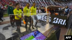 L'arbitre brésilien Wilton Pereira Sampaio (C) et ses assistants passent devant un écran de l'assistance vidéo à l'arbitrage(VAR) avant le début de la demi-finale de la Copa Libertadores 2017 au stade Monumental de Buenos Aires, le 25 octobre 2017.