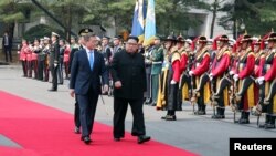 Presiden Korea Selatan Moon Jae-in dan pemimpin Korea Utara Kim Jong-un menghadiri upacara penyambutan di Wisma Perdamaian (Peace House) di desa gencatan senjata Panmunjom di dalam zona demiliterisasi yang memisahkan kedua Korea, Korea Selatan, 27 April 2018.