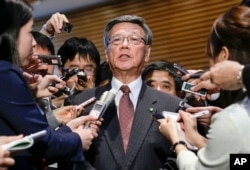 FILE - Okinawa Gov. Takeshi Onaga is surrounded by reporters after a meeting with Japanese Prime Minister Shinzo Abe at the latter's official residence in Tokyo.