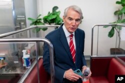 FILE - Senator Rob Portman talks to reporters as he takes a Senate subway train on Capitol Hill in Washington, July 30, 2021.