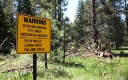 FILE - A warning sign is seen for hikers entering the area burned in the 2007 Angora fire, near South Lake Tahoe, Calif., July 6, 2010.