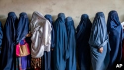 FILE - Afghan women wait to receive food distributed by a humanitarian aid group in Kabul, Afghanistan, on May 23, 2023. The United States on Dec. 8 imposed sanctions against two Taliban leaders for human rights abuses against women and girls.