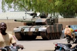 FILE - People drive past a Chad army tank near the presidential palace, as fighters from the rebel Front for Change and Concord in Chad (FACT) appeared to be moving toward the capital, according to the US, in N'djamena,  Apr. 19, 2021.