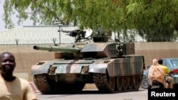 People drive past a Chad army tank near the presidential palace, as fighters from the rebel Front for Change and Concord in Chad (FACT) appeared to be moving toward the capital, according to the United States, in N'djamena, Chad, April 19, 2021. 