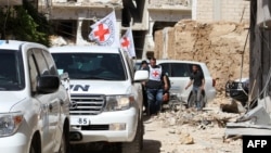 Vehicles of the International Committee of the Red Cross and the United Nations wait on a street after an aid convoy entered the rebel-held Syrian town of Daraya, southwest of the capital Damascus, June 1, 2016.