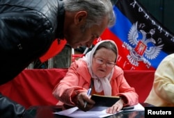 A woman checks documents of a Ukrainian man before issuing him a paper ballot in Moscow, Russia, May 11, 2014. Many Ukrainians living in Moscow came to vote as well.