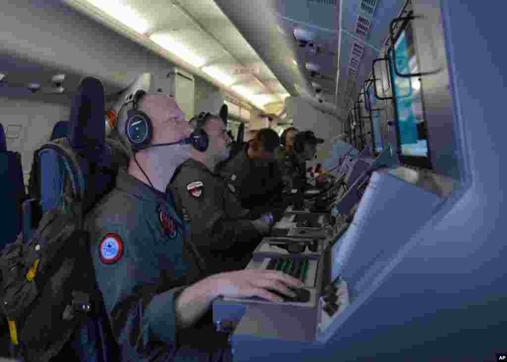 In this photo provided by the U.S. Navy, crew members on board an aircraft P-8A Poseidon assist in the search and rescue operations for Malaysia Airlines flight MH370 in the Indian Ocean,&nbsp; March 16, 2014. 