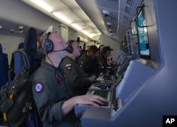 In this photo provided by the U.S. Navy, crew members on board an aircraft P-8A Poseidon assist in search and rescue operations for Malaysia Airlines flight MH370 in the Indian Ocean, March 16, 2014.