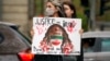 (FILE) A woman holds a placard as she crosses a street to join a protest against the death of Iranian Mahsa Amini, in Bucharest, Romania, Saturday, Oct. 1, 2022.