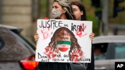 (FILE) A woman holds a placard as she crosses a street to join a protest against the death of Iranian Mahsa Amini, in Bucharest, Romania, Saturday, Oct. 1, 2022.