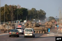 Las fuerzas israelíes cruzan una carretera principal con sus obuses autopropulsados mientras se despliegan tropas adicionales cerca de la ciudad sureña de Sderot el 8 de octubre de 2023.