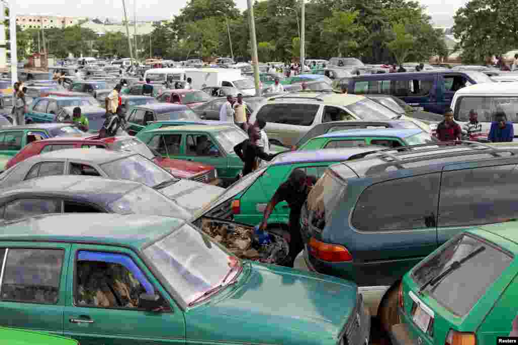 Um homem coloca água no radiador do carro enquanto espera nas filas incríveis para abastecer o carro.&nbsp; Abuja, Nigéria 25 de Maio 2015