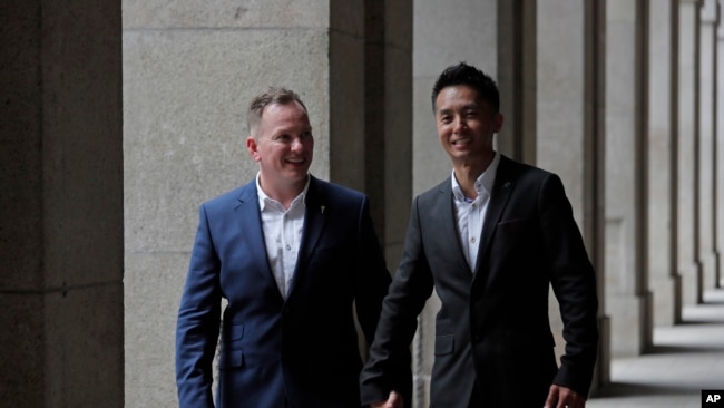 香港移民官梁镇罡和他的英籍同性婚姻伴侣史葛携手走在香港终审法院外。(2019年6月6日)