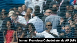 Cuban President Raul Castro, right, cheers next to U.S. President Barack Obama, his wife Michelle, and their daughters Sasha and Malia, at the start of a baseball game between the Tampa Bay Rays and the Cuban national baseball team, in Havana, Cuba, Tuesd