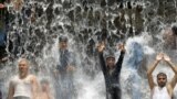 Pakistani youth crowd a water fall in a park to beat the heat in Lahore. Severe heat wave conditions continue over most plains of the Punjab province.