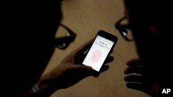 FILE - An Apple employee instructs a journalist on the use of the fingerprint scanner technology built into the company's iPhone 5S during a media event in Beijing, Sept. 11, 2013. Watchdog groups are concerned that U.S. Customs and Border Protection agents are searching the digital devices of international travelers at border checkpoints in U.S. airports. 