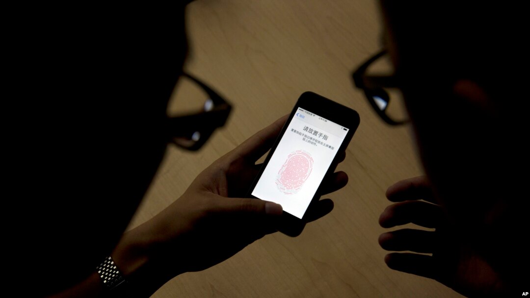 FILE - An Apple employee instructs a journalist on the use of the fingerprint scanner technology built into the company's iPhone 5S during a media event in Beijing, Sept. 11, 2013. Watchdog groups are concerned that U.S. Customs and Border Protection agents are searching the digital devices of international travelers at border checkpoints in U.S. airports. 