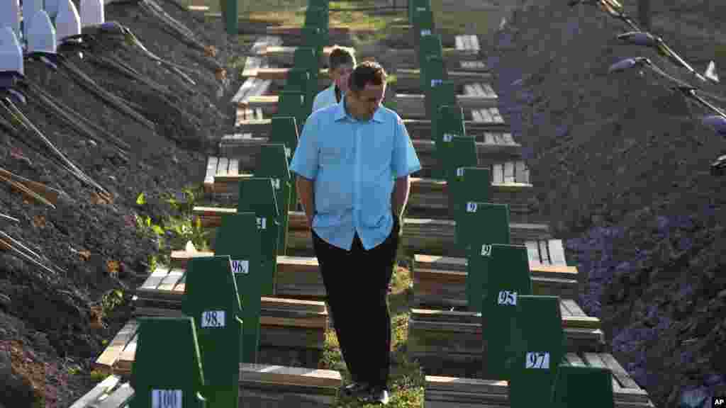 A Bosnian man walks among graves during a funeral ceremony for the 136 victims at the Potocari memorial complex near Srebrenica, 150 kilometers (94 miles) northeast of Sarajevo, Bosnia and Herzegovina, July 11, 2015. 