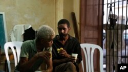 In this Aug. 21, 2015, photo, men helped by the San Egidio Church eat snacks in its community center in Havana, Cuba.