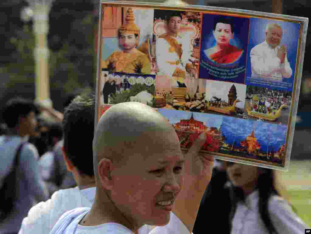 A Buddhist nun holds the portraits of Cambodia's late King Norodom Sihanouk Thursday, Jan. 31, 2013, in Phnom Penh, Cambodia. The body of Sihanouk who died on Oct. 15, 2012 at age 89, is scheduled to be cremated on Feb. 4, 2013. (AP Photo/Heng Sinith)