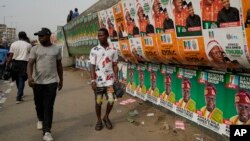 Young people walk past election campaign posters in the capital Lagos, Feb. 21, 2023.