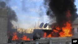 In this Feb. 22, 2012 citizen journalism image provided by the Local Coordination Committees in Syria, flames rise from a house from Syrian government shelling, at Baba Amr neighborhood in Homs province.