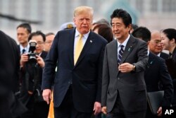 U.S. President Donald Trump, center, with Japan's Prime Minister Shinzo Abe, leaves the Japanese destroyer JS Kaga, after his tour in Yokosuka, south of Tokyo, May 28, 2019.