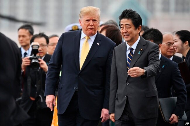 U.S. President Donald Trump, center, with Japan's Prime Minister Shinzo Abe, leaves the Japanese destroyer JS Kaga, after his tour in Yokosuka, south of Tokyo, May 28, 2019.