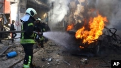 Para petugas kelompok pertahanan sipil Suriah White Helmet berusaha memadamkan kobaran api pada mobil yang terbakar akibat serangan roket yang melanda kota Afrin, Suriah, pada 20 Januri 2022. (Foto: Syrian Civil Defense White Helmets via AP)