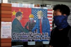 FILE - A pro-democracy protester walks past a poster featuring Chinese President Xi Jinping, left, and U.S. President Donald Trump at the campus of the University of Hong Kong, in Hong Kong, Nov. 6, 2019.