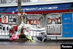 FILE - Flowers and messages in tribute to the victims of last year's January attacks are seen in front of the Hyper Cacher kosher supermarket at the Porte de Vincennes in Paris, France, Jan. 6, 2016.