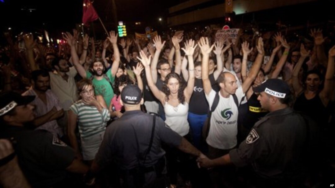 Para aktivis Israel mengangkat tangan mereka saat berunjuk rasa di Tel Aviv (24/6). Pihak berwenang telah menangkap sedikitnya 85 orang pasca bentrokan demonstran dan polisi dan pengrusakan di bank-bank di ibukota Israel ini.