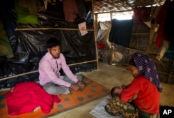 In this Jan. 14, 2018 photo, Rohingya Muslim refugee Mohammad Lalmia, 20, from the Myanmar village of Gu Dar Pyin, sits inside a makeshift shelter in Balukhali refugee camp, Bangladesh.