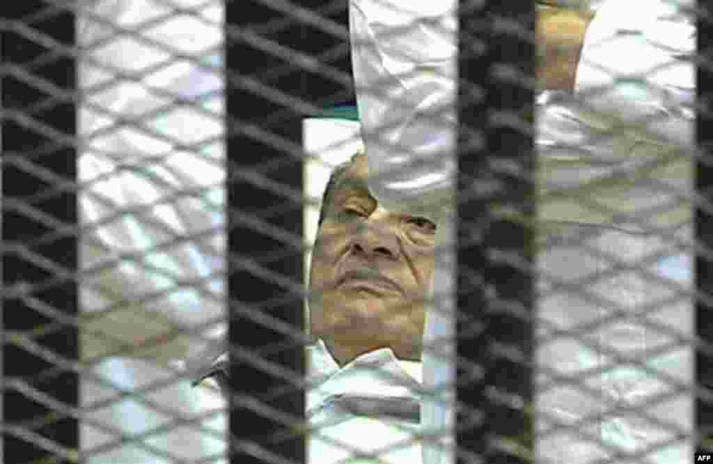 This video image taken from Egyptian State Television showing 83-year-old former Egyptian president Hosni Mubarak laying on a hospital bed flanked by his two sons Gamal and Alaa, inside a cage of mesh and iron bars in a Cairo courtroom Wednesday Aug. 3, 2