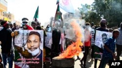 Des Soudanais portent des affiches de manifestants tués alors qu'ils protestent dans la capitale Khartoum contre le coup d'État du 25 octobre, le 30 décembre 2021.