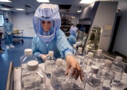FILE - A laboratory worker simulates the workflow in a cleanroom of the BioNTech Corona vaccine production facility in Marburg, Germany, during a media day, March 27, 2021.