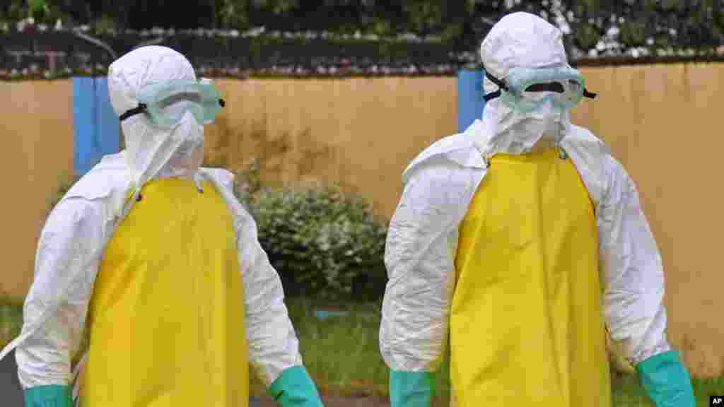 Health workers wearing protective gear go to remove the body of a person who is believed to have died after contracting the Ebola virus in Monrovia, August 16, 2014.