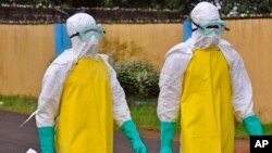 Petugas kesehatan Liberia mengenakan pakaian pelindung untuk memindahkan jenazah bekas pasien ebola di Monrovia (16/8).