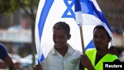 FILE - African migrants from Eritrea hold an Israeli flag during a protest near the Ministry of Defense in Tel Aviv, October 18, 2012.