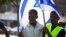 FILE - African migrants from Eritrea hold an Israeli flag during a protest near the Ministry of Defense in Tel Aviv, October 18, 2012.