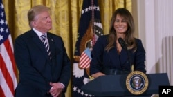 President Donald Trump looks to first lady Melania Trump as she speaks in the East Room of the White House in Washington, May 9, 2018, during an event celebrating military mothers and spouses. 