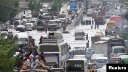 People and vehicles pass through a flooded road after the rain in Karachi, Pakistan, Aug. 31, 2017.
