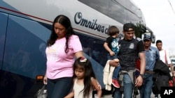 Migrantes centroamericanos se preparan para abordar un autobús en el que voluntariamente regresan a sus países. Ciudad Juárez, México, martes, 2 de julio de 2019. 